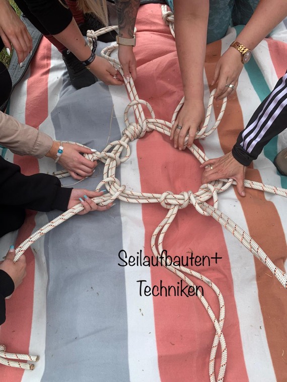 Mehrere Hände knüpfen gemeinsam einen Seilstern