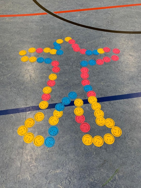 Eine Figur aus bunten Smiley-Karten auf dem Hallenboden